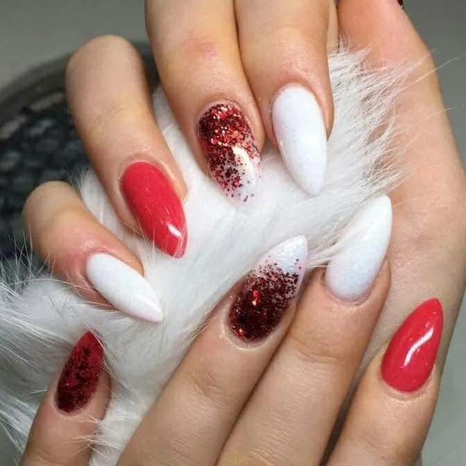 Almond nails in glossy red, red glitter and white, resting on white fluffy fabric